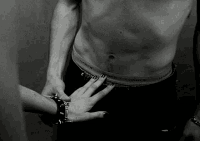 a black and white photo of a woman touching a shirtless man 's waistband that says hanes