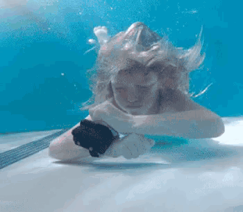 a person is swimming underwater in a pool and holding a black object