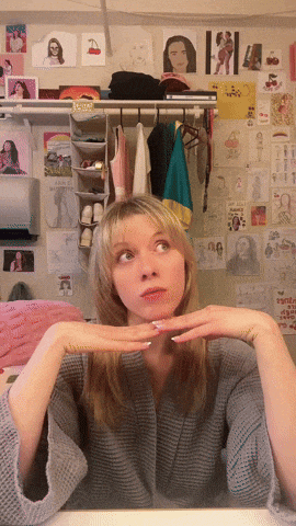 a girl sitting in front of a wall with drawings on it and a sign that says ' i love you ' on it