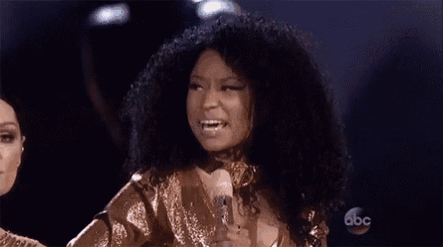 a woman with curly hair is holding a microphone and smiling .