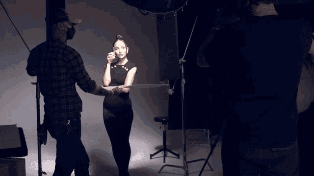 a woman in a black dress is standing in front of a camera