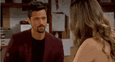 a man and a woman are looking at each other in a room