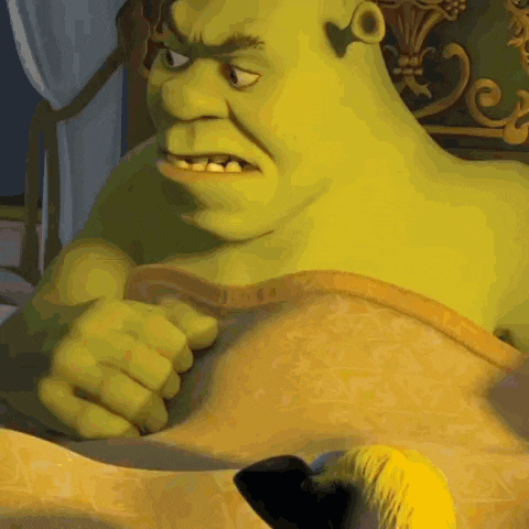 shrek from shrek is laying in bed with a blanket on