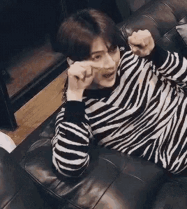 a man in a striped sweater is laying on a couch .