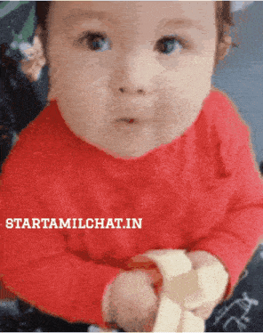 a baby in a red shirt is holding a banana and the website starttamilchat.in is below it