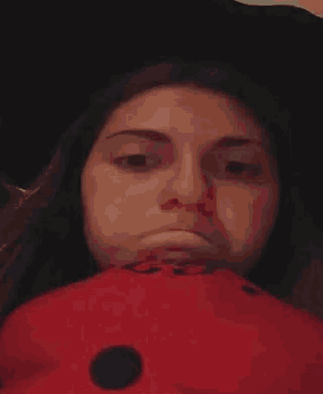 a woman is making a funny face while laying on a red pillow .