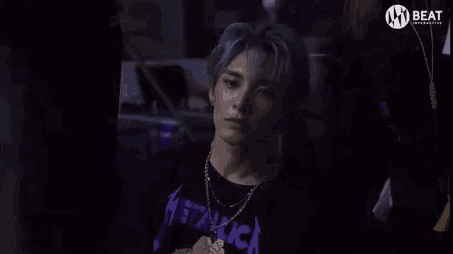 a man with blue hair is sitting in a dark room .