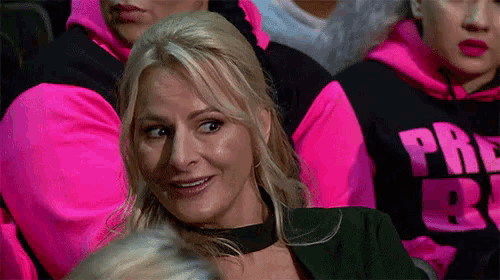 a woman is sitting in a crowd wearing a choker and a pink shirt .