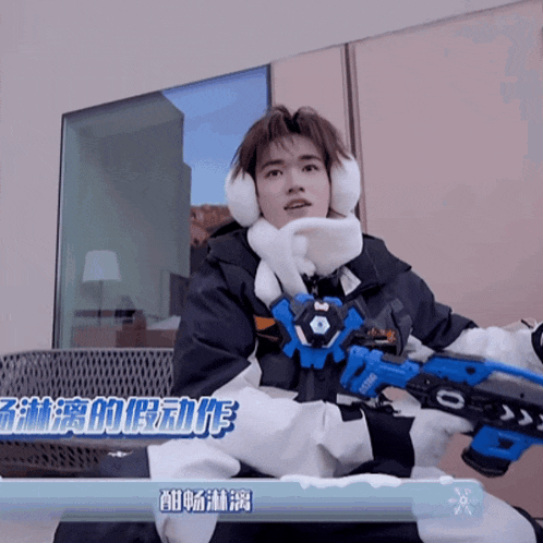 a man wearing ear muffs and holding a toy gun with the number 0