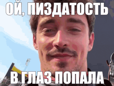 a man with a beard and mustache looks at the camera with a foreign language caption