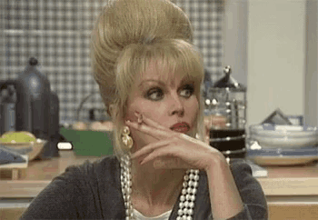 a woman with blonde hair and a pearl necklace is sitting at a table .