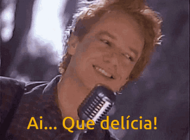 a man singing into a microphone with the words " ai que delicia " above him