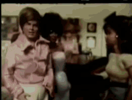 a man in a pink shirt is standing next to two women in a room .