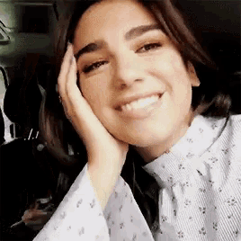 a close up of a woman smiling with her hand on her face .