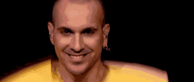 a close up of a man wearing a yellow jacket and smiling on a stage .