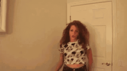 a woman with red hair is wearing a mickey mouse shirt and dancing .