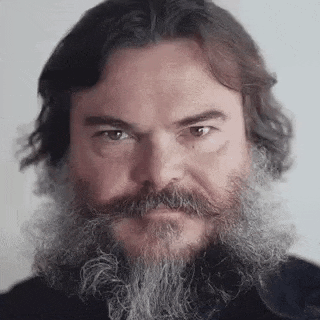 a man with a long beard and mustache is looking at the camera .
