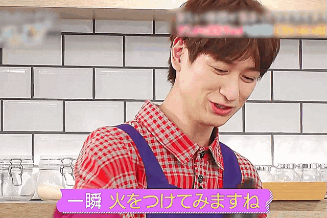 a man wearing a plaid shirt and an apron is smiling in a kitchen