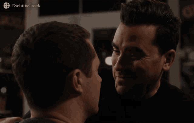 a man kissing another man with the hashtag schitts creek on the bottom