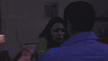 a man and a woman are standing in a room with blue lights .