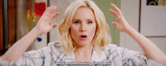 a woman is making a funny face with her hands in the air and says holy motherforking shirtballs .