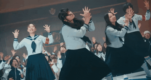 a group of girls in school uniforms are dancing in a room