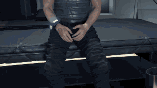 a man is sitting on a bed with his hands on his belly