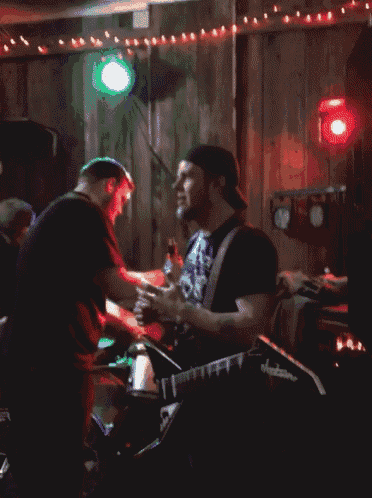 a man playing a guitar in a dark room with a red light behind him