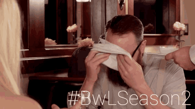 a man with a beard is covering his face with a napkin with the hashtag # bwl season 2 on the bottom