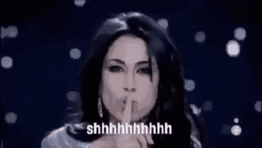 a woman is making a shhh gesture with her finger to her mouth .