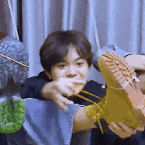a man is holding a pair of boots in his hands and making a funny face .
