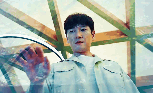 a man in a white shirt is standing in front of a glass wall with a reflection of a building in the glass