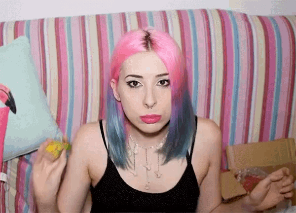 a girl with pink and blue hair is sitting on a couch