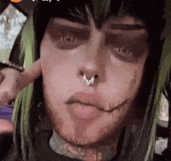 a close up of a person 's face with a nose ring and green hair