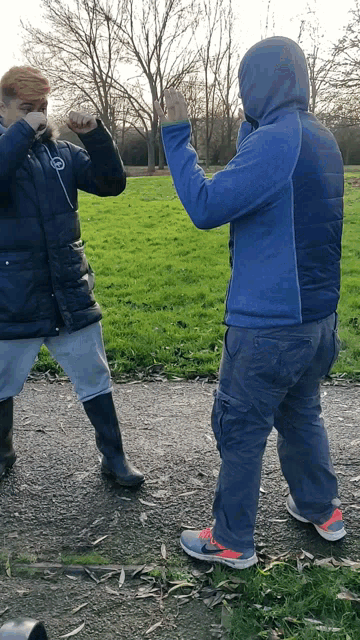 a man wearing a blue jacket with a hood stands next to another man