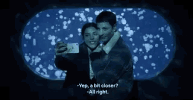 a man and woman are taking a selfie in front of a jellyfish tank and the man says it looks great smile you like it
