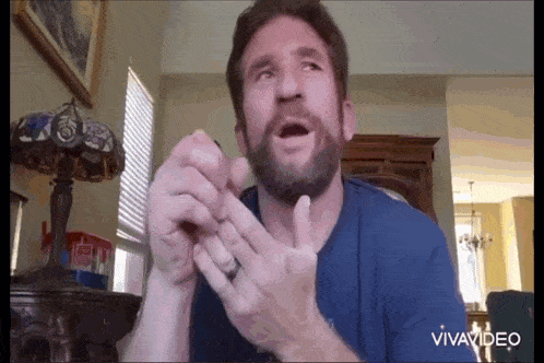 a man with a beard is making a funny face while holding his hands together .