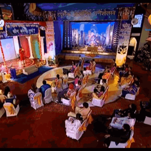 a group of people sitting in chairs in front of a stage with a sign that says ' shree ' on it