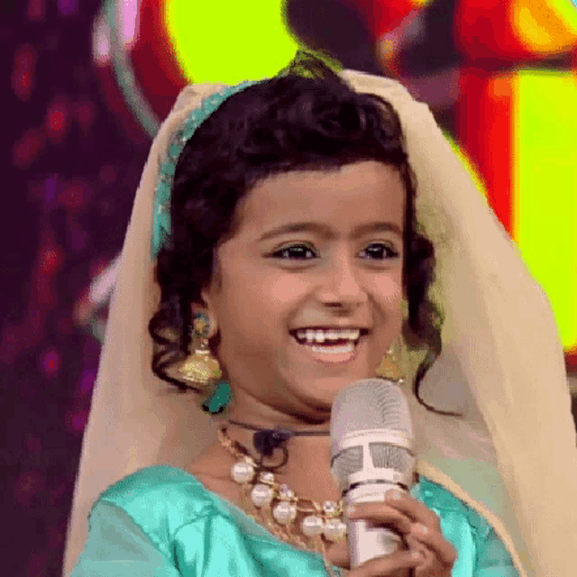a little girl is holding a microphone and smiling for the camera