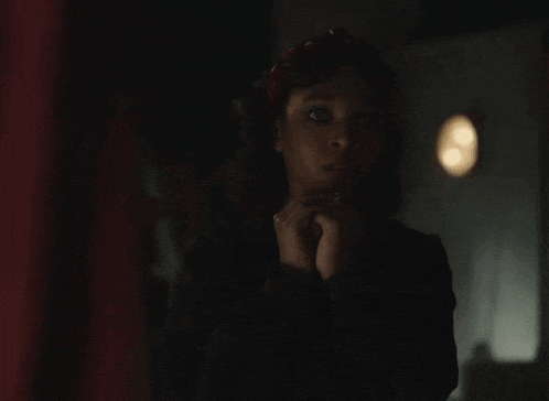 a woman in a dark room is making a gesture with her hand