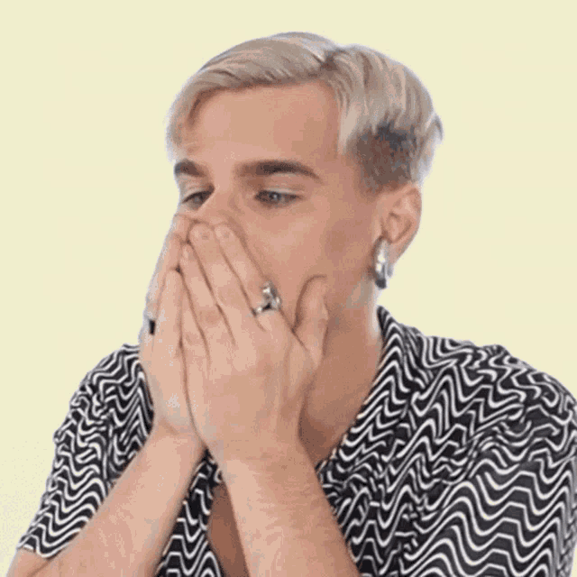 a man with a ring on his finger covering his mouth