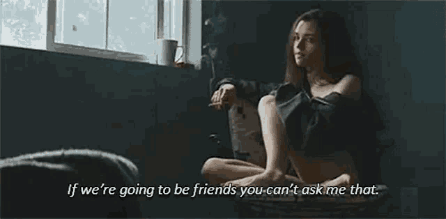 a woman is sitting on a window sill smoking a cigarette and talking to someone .