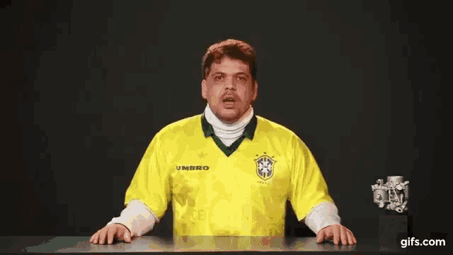 a man wearing a yellow umbro shirt is standing in front of a black background