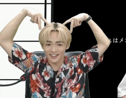 a young man wearing a floral shirt is making a heart shape with his hands