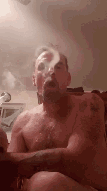 a man without a shirt is smoking a cigarette