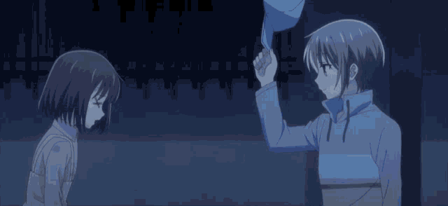 a boy and a girl are touching each other 's hats in a dark room .
