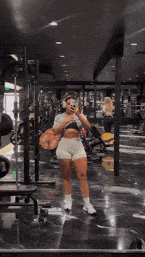 a woman is taking a picture of herself in a gym mirror
