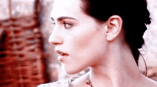 a close up of a woman 's face with a necklace on .