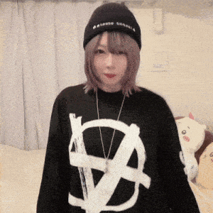 a woman wearing a black hat and a black shirt with an anarchy symbol on it