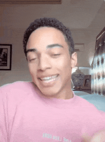 a young man wearing a pink shirt that says ' nike ' on it smiles